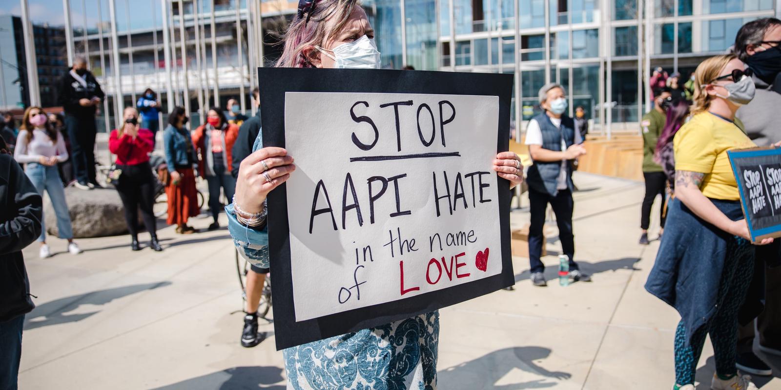 Woman holding sign that reads "Stop AAPI hate in the name of love"