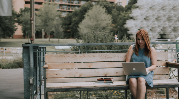 Young adult on bench on her laptop