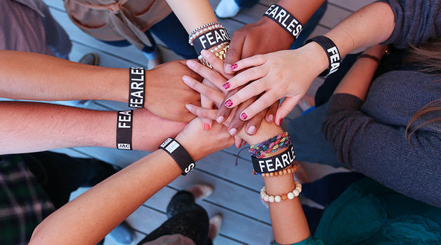 People's hands all in the middle with the Zeno fearless bracelets on