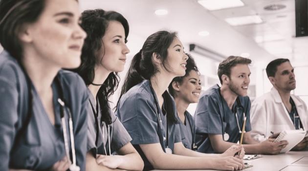 Millennial physicians shoulder-to-shoulder leaning on a table