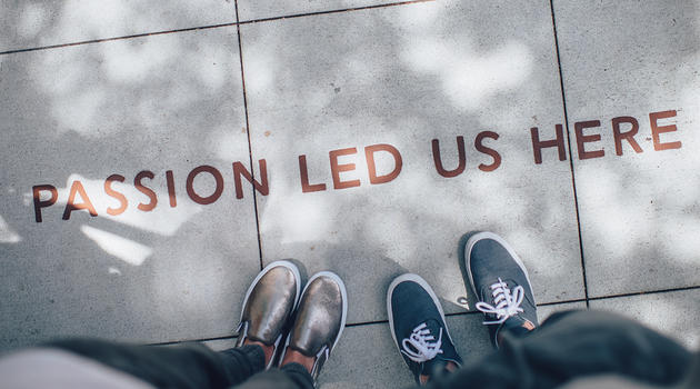 Two pairs of shoes standing on sidewalk that says passion led us here