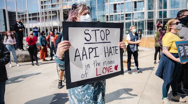 Woman holding sign that reads "Stop AAPI hate in the name of love"