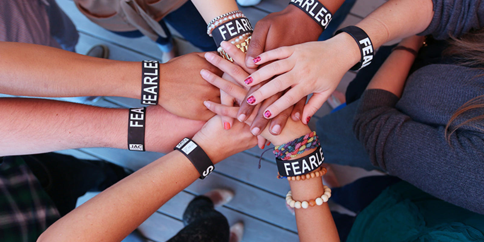 People's hands all in the middle with the Zeno fearless bracelets on