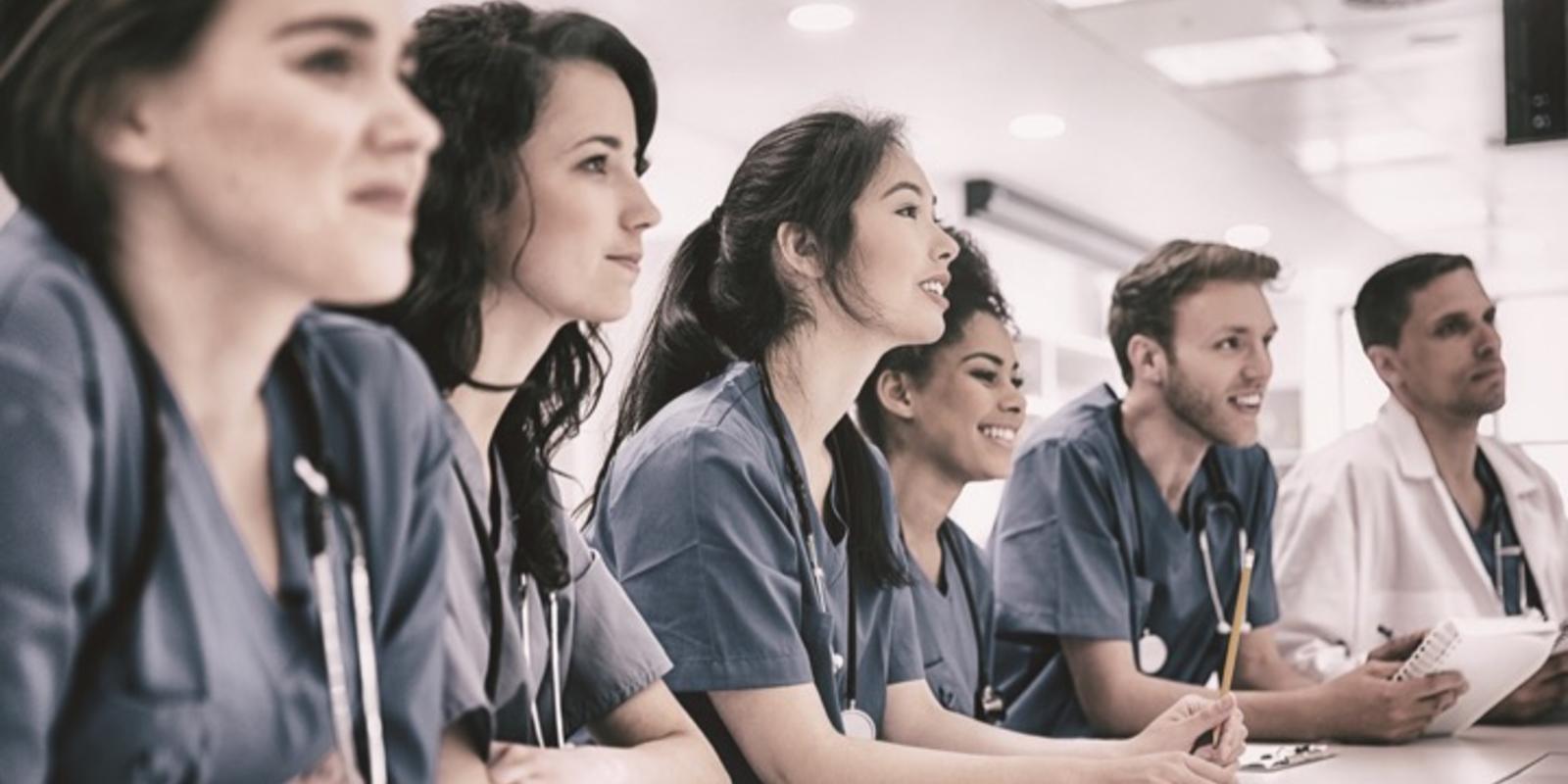 Millennial physicians shoulder-to-shoulder leaning on a table