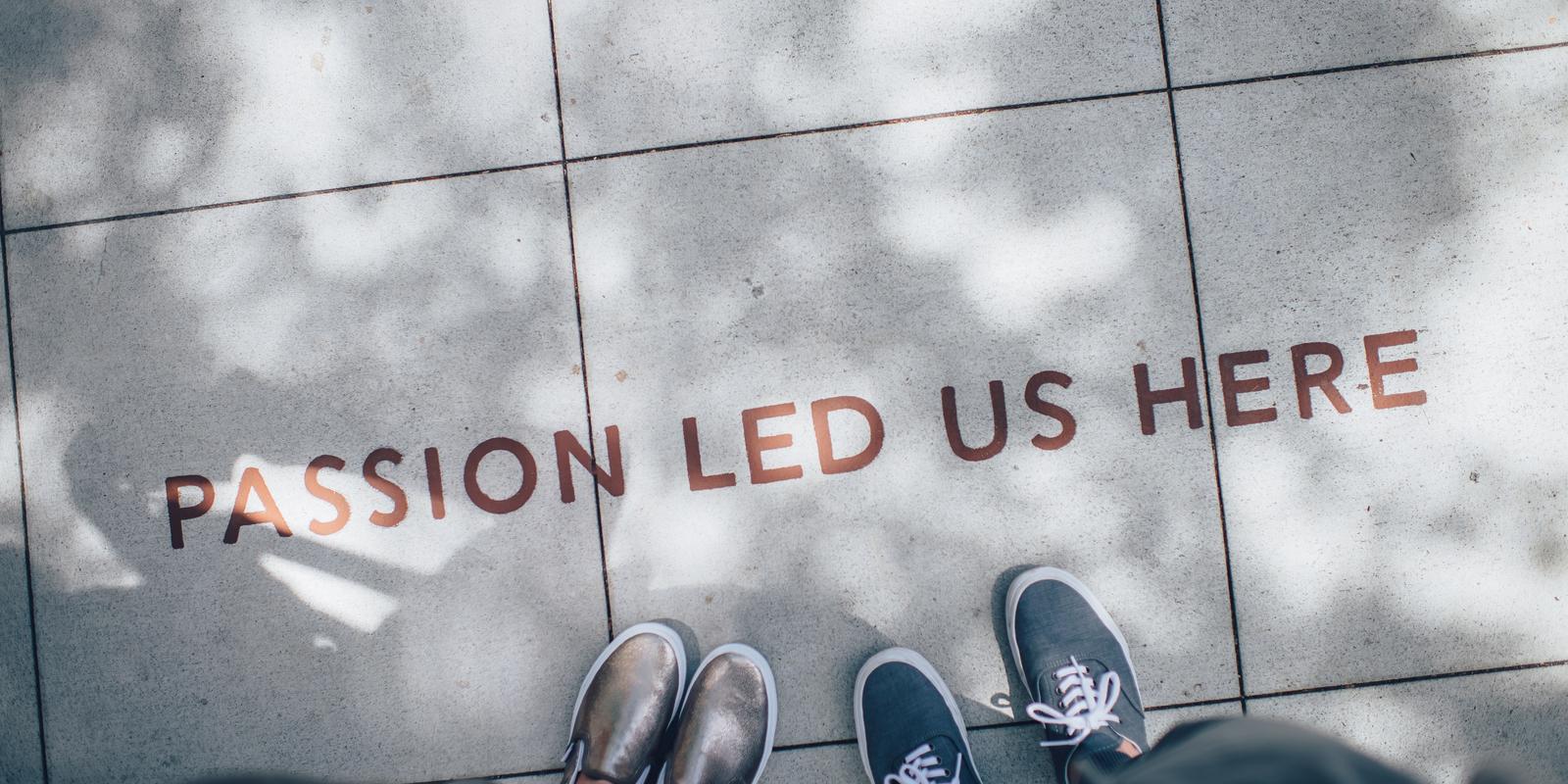 Two pairs of shoes on sidewalk that says passion led us here